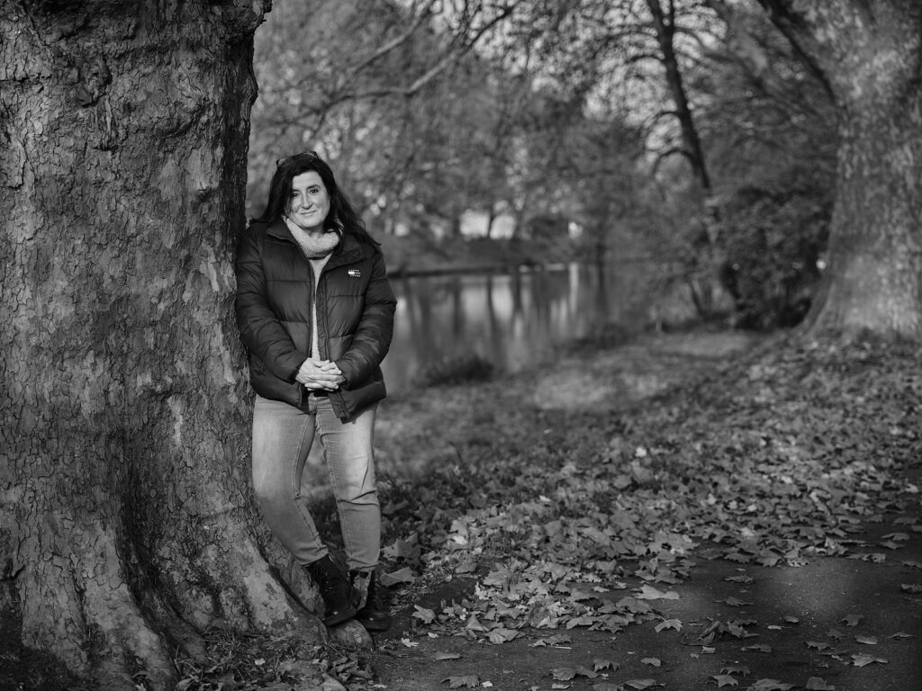 Frau lehnt sich an den Stamm einer Platane an