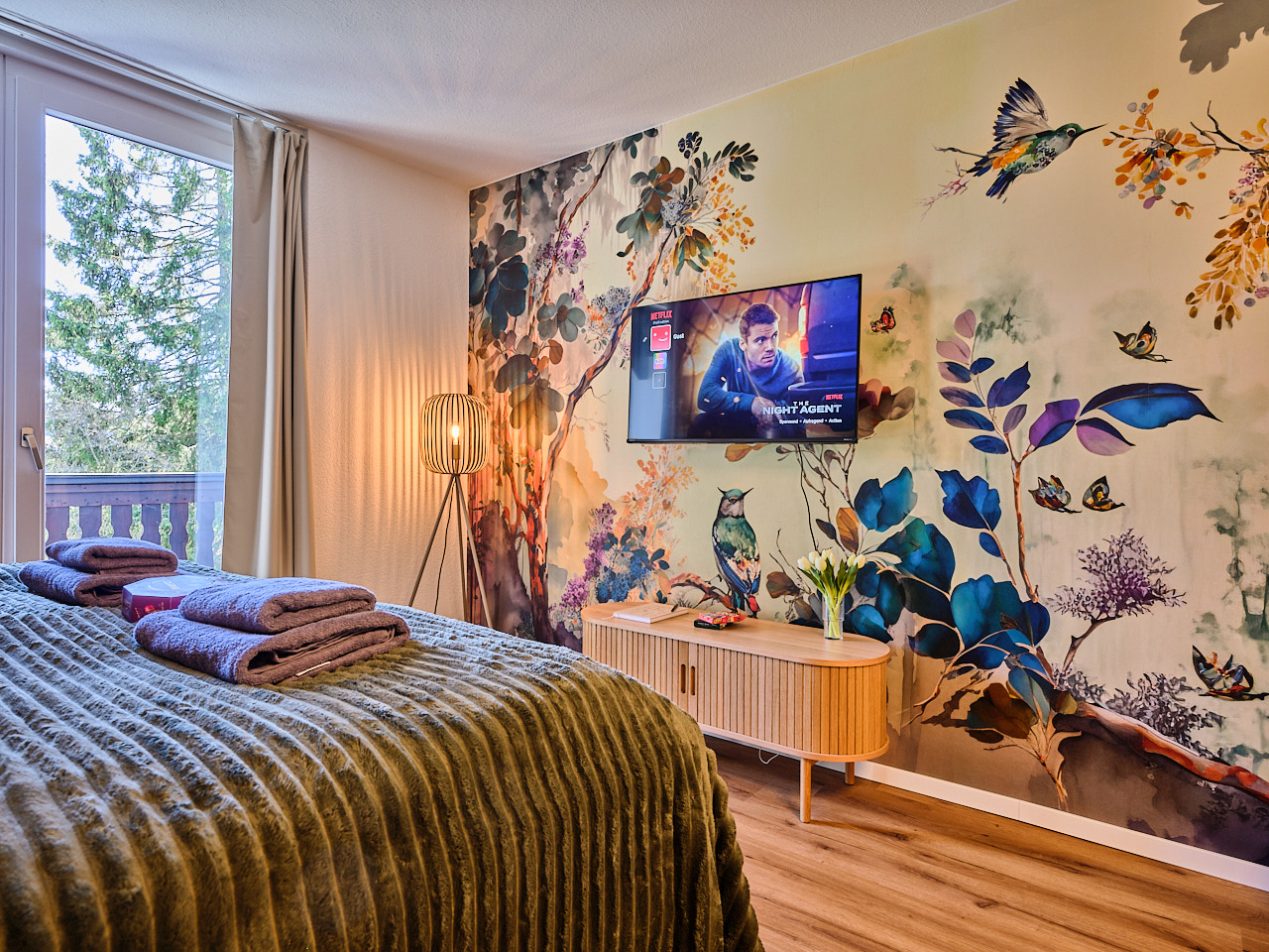 Immobilienfotografie: Gemütliche Ferienwohnung. Blick über das Bett in Richtung Fernseher